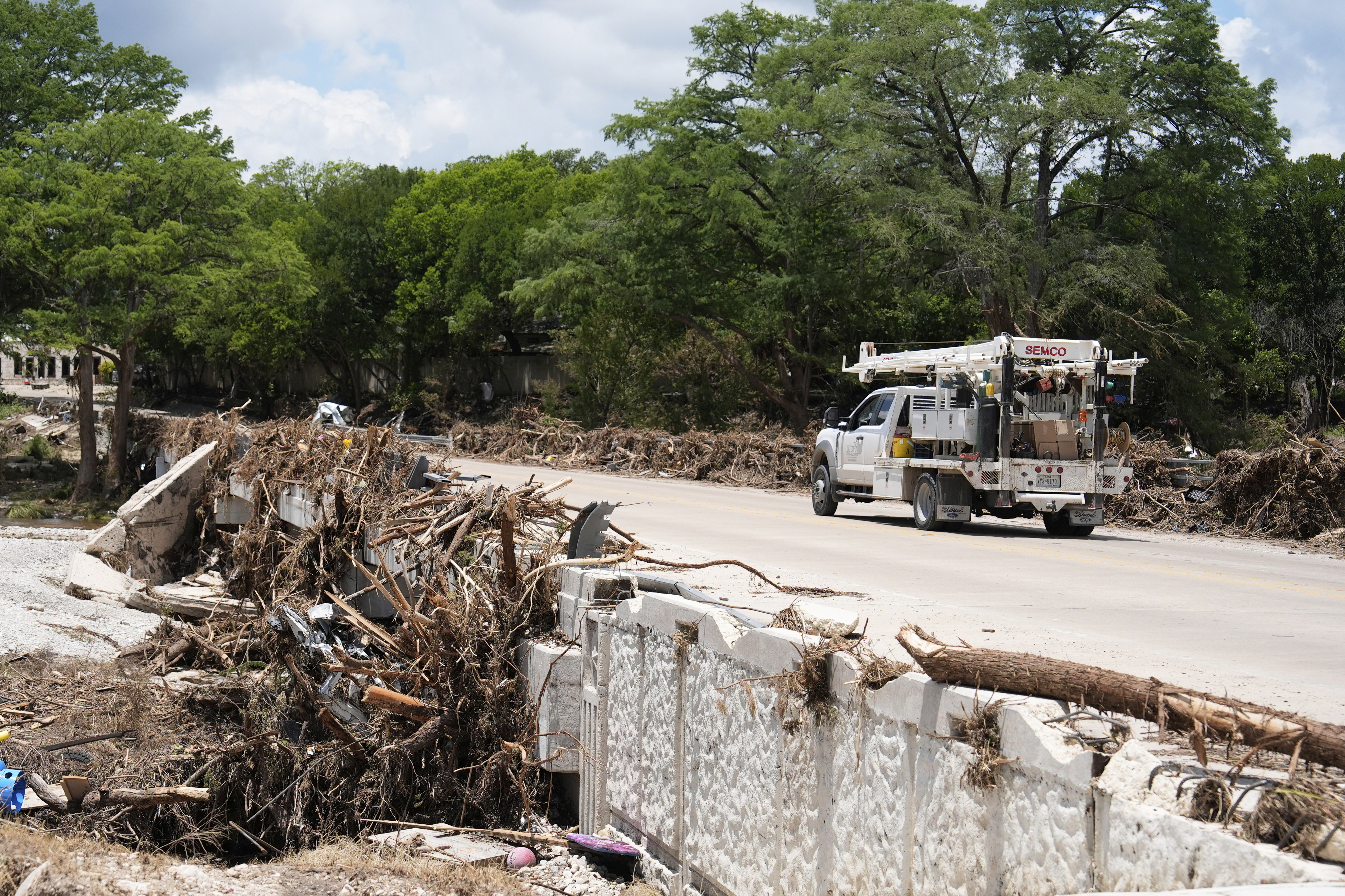 A utility truck drives past debris from a flood in...