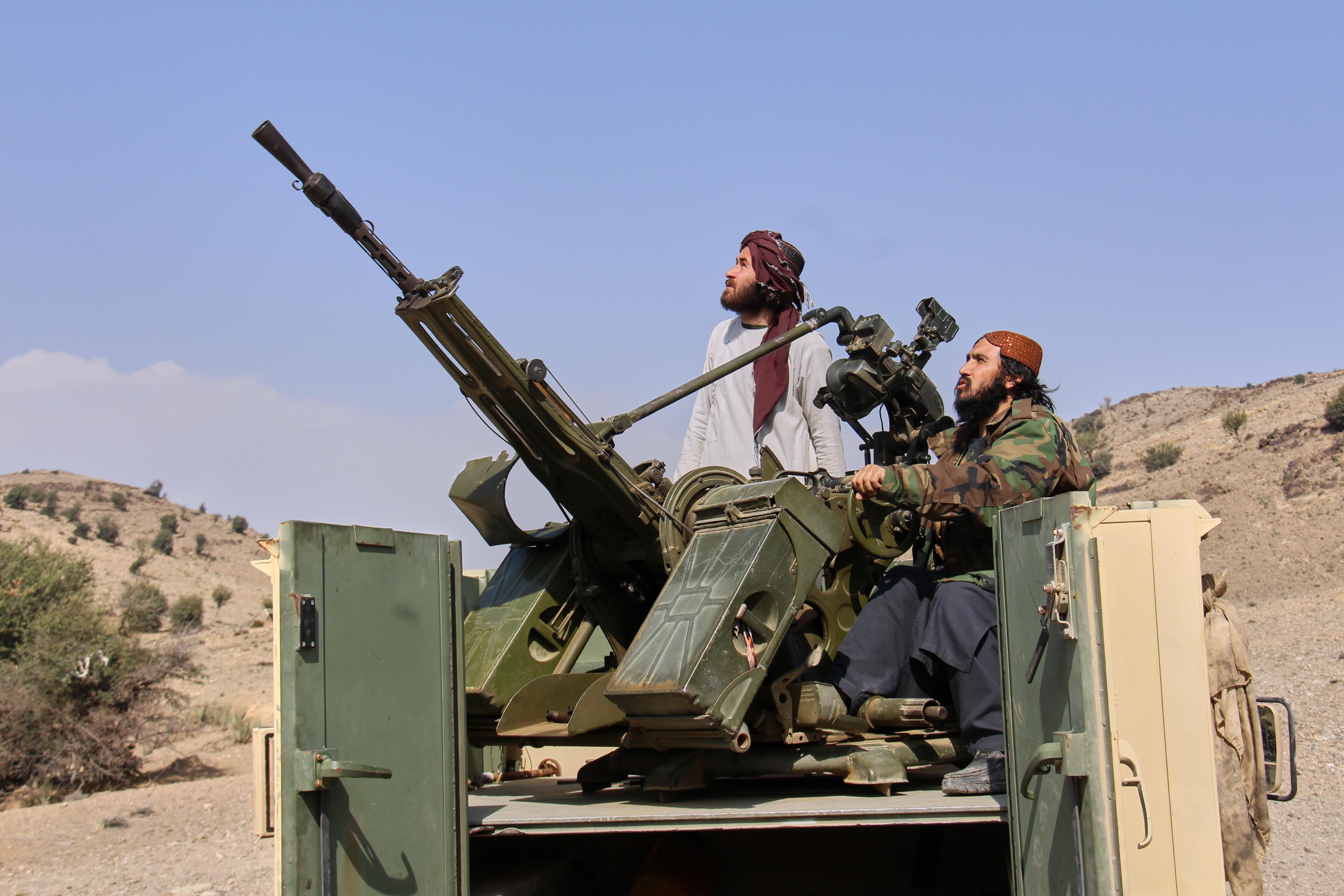 Taliban fighters look up while manning an armed pickup truck.