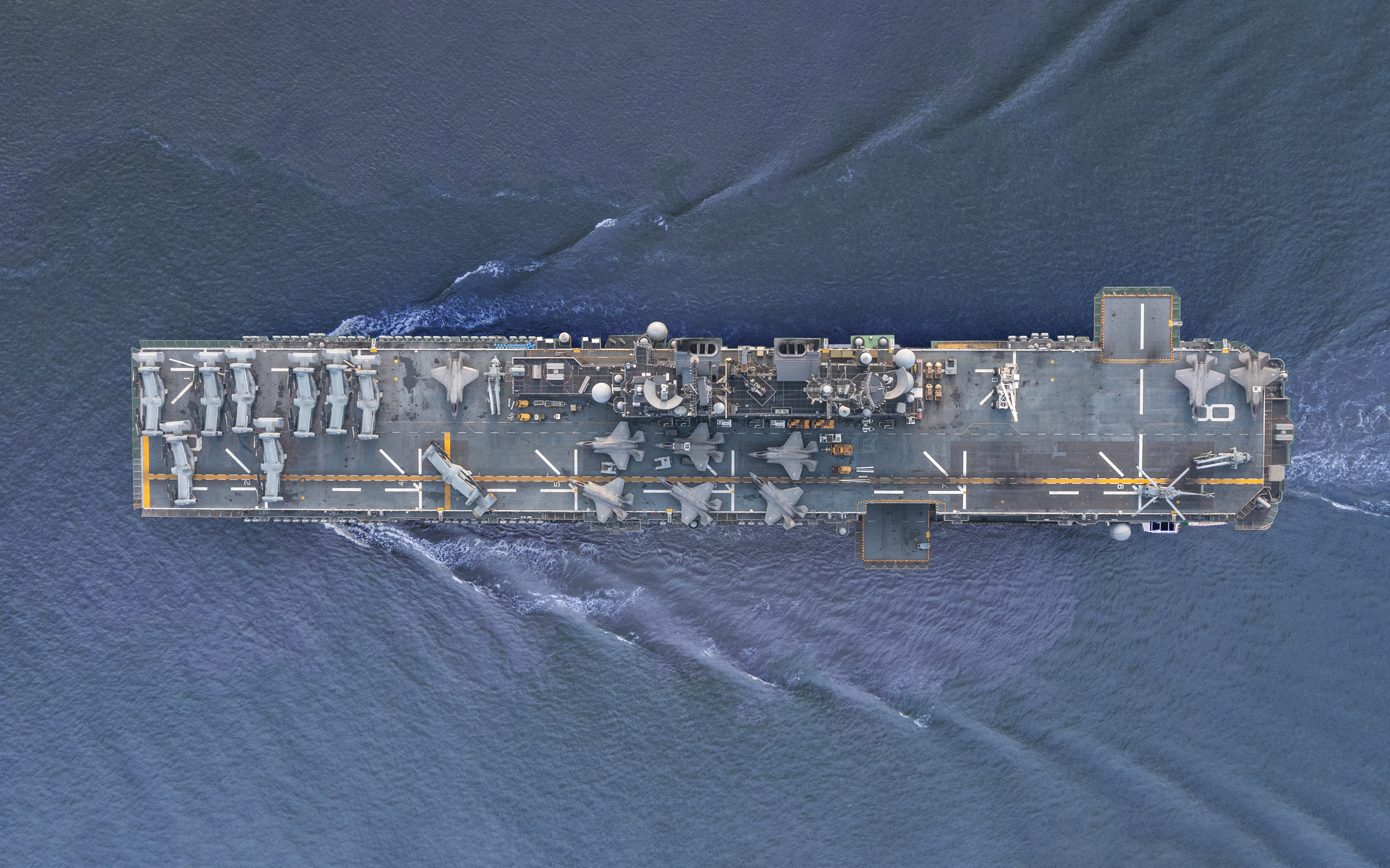 Aerial view/A fighter aircraft carrier sailing in the middle of the sea.