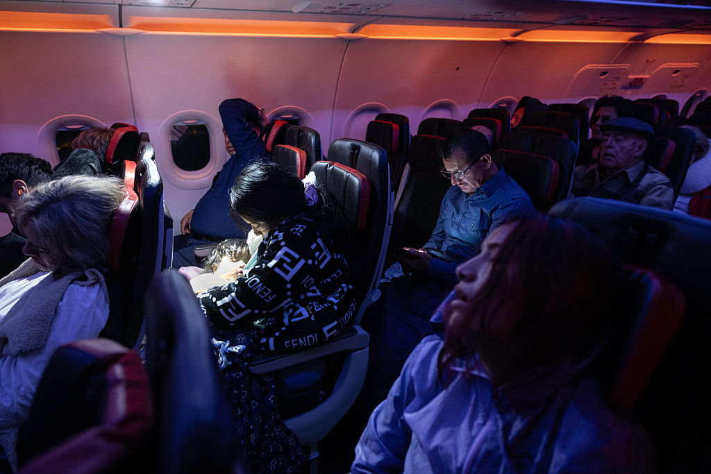 Undocumented mother Andrea, 28, (L) and her cousin Jennyfer, 22, (R) sleep on their overnight flight to Ecuador from JFK International Airport on Oct. 27, 2025.