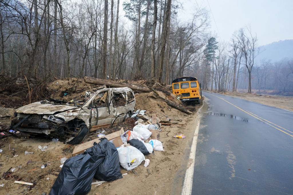 Debris from Hurricane Helene litters the side of the road as smoke hangs in the air near the Black Cove wildfire on March 24, 2025 in Polk County, North Carolina. Three large wildfires have burned more than 3,000 acres as evacuation orders were issued for parts of Polk County. 