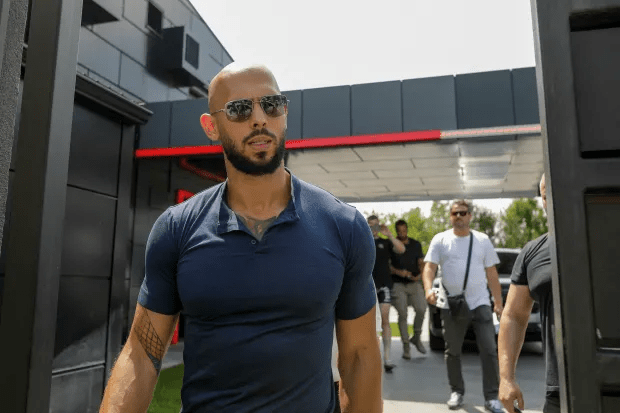 Man in sunglasses walking through a gate.