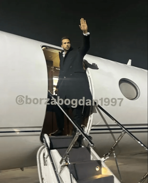 Man in suit waving goodbye from a private jet.