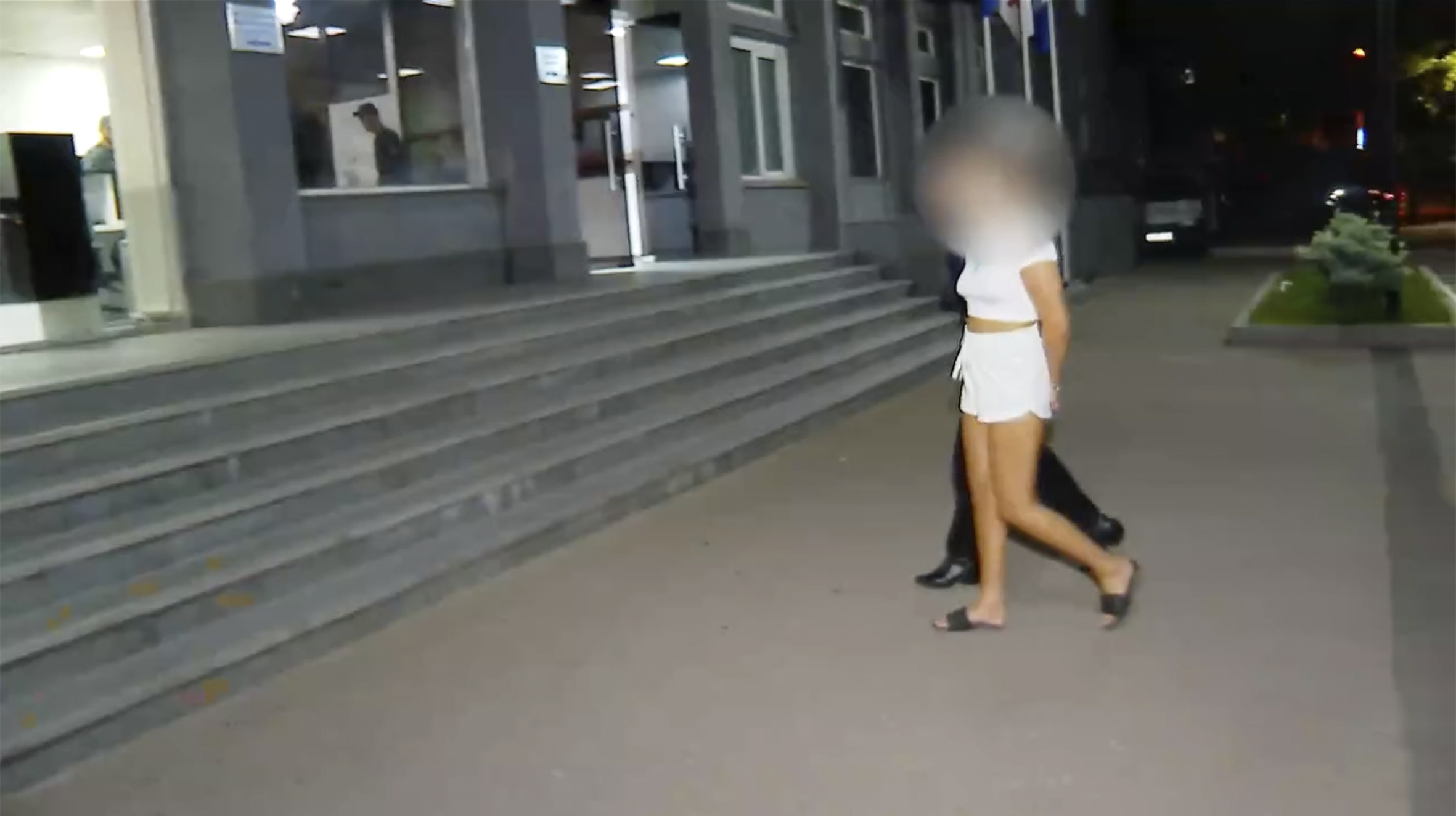 A British woman in handcuffs escorted by police.