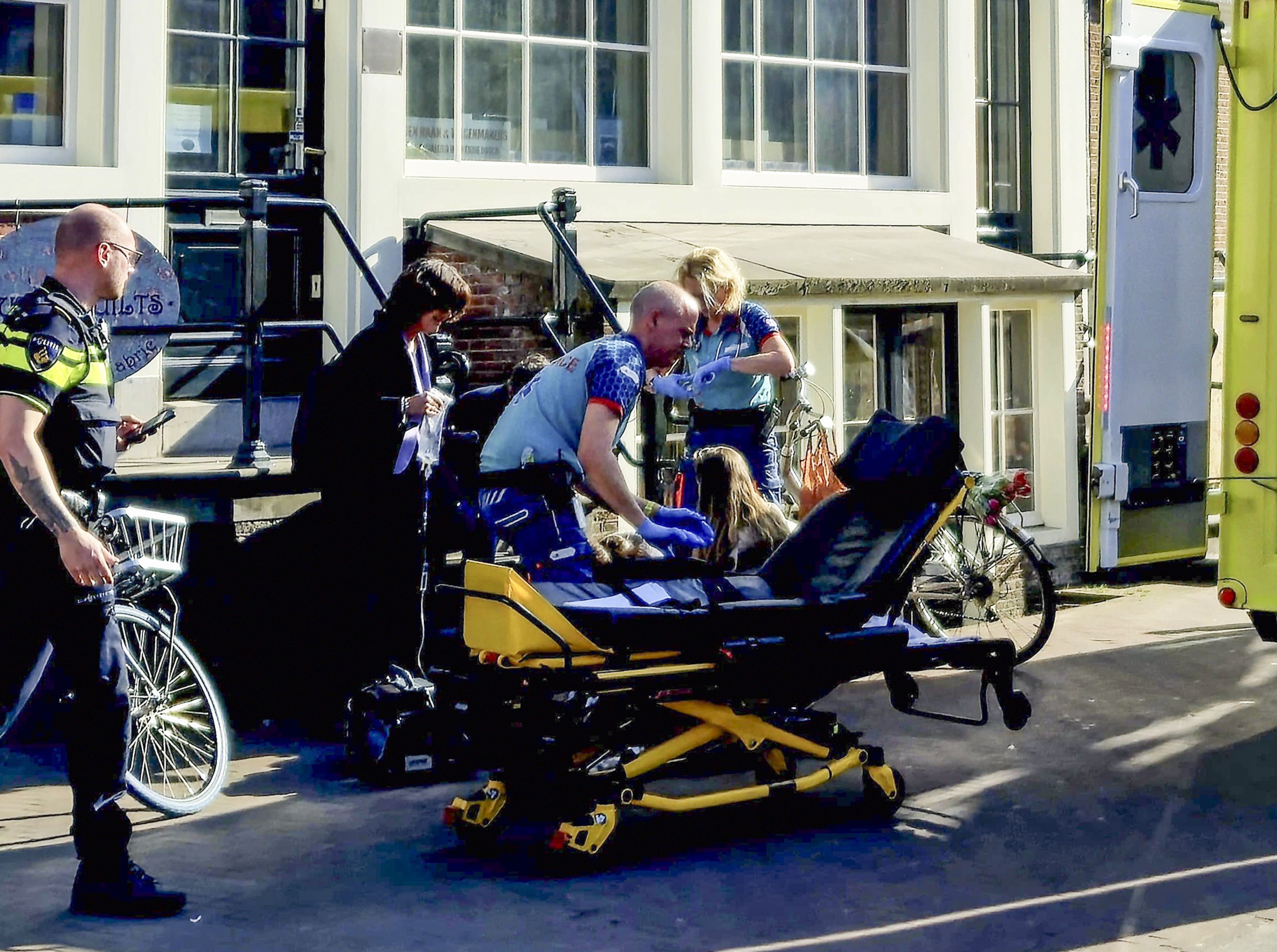 A stabbing victim on a stretcher being helped by paramedics near an ambulance.