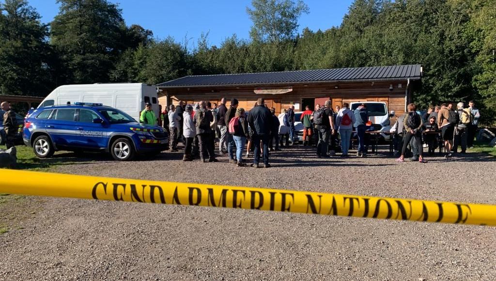 a group of people are standing in front of a building behind a yellow caution tape