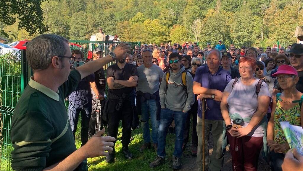 a man stands in front of a crowd of people and points at something