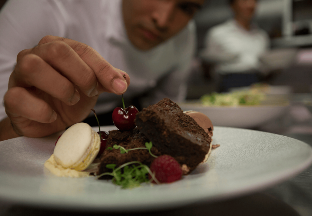 Male chef garnishing dessert in plate